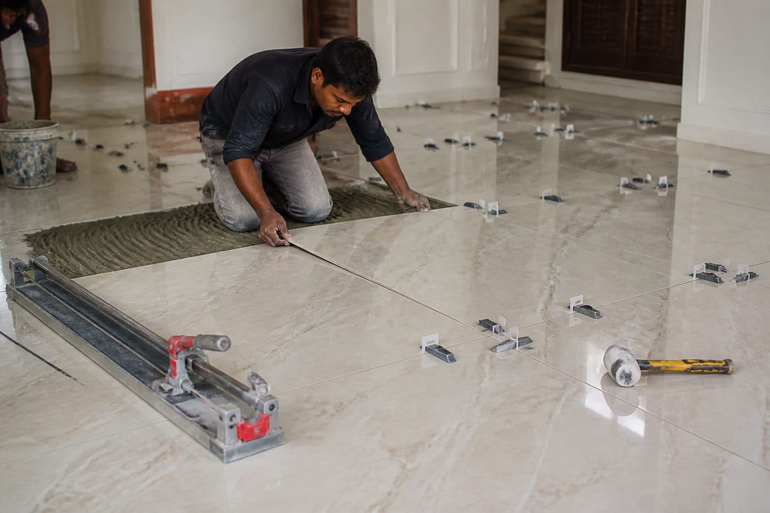 Large-format vitrified floor tiles being levelled in a Pune bungalow